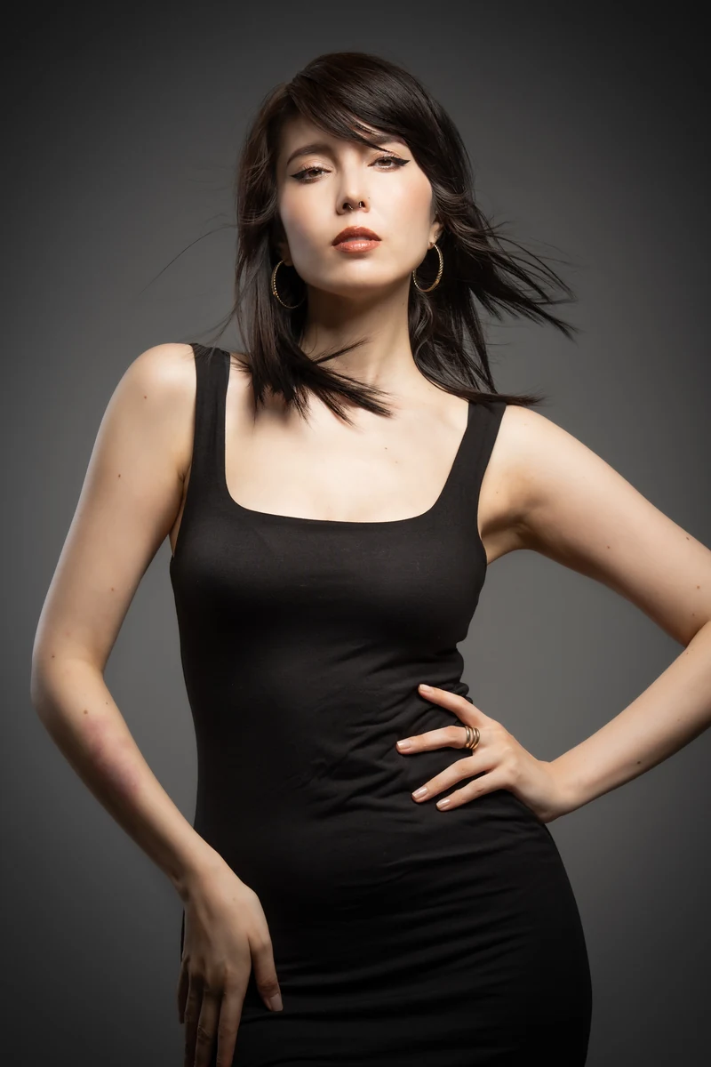 Samantha Mariko wearing a black dress against a dark gray studio backdrop.